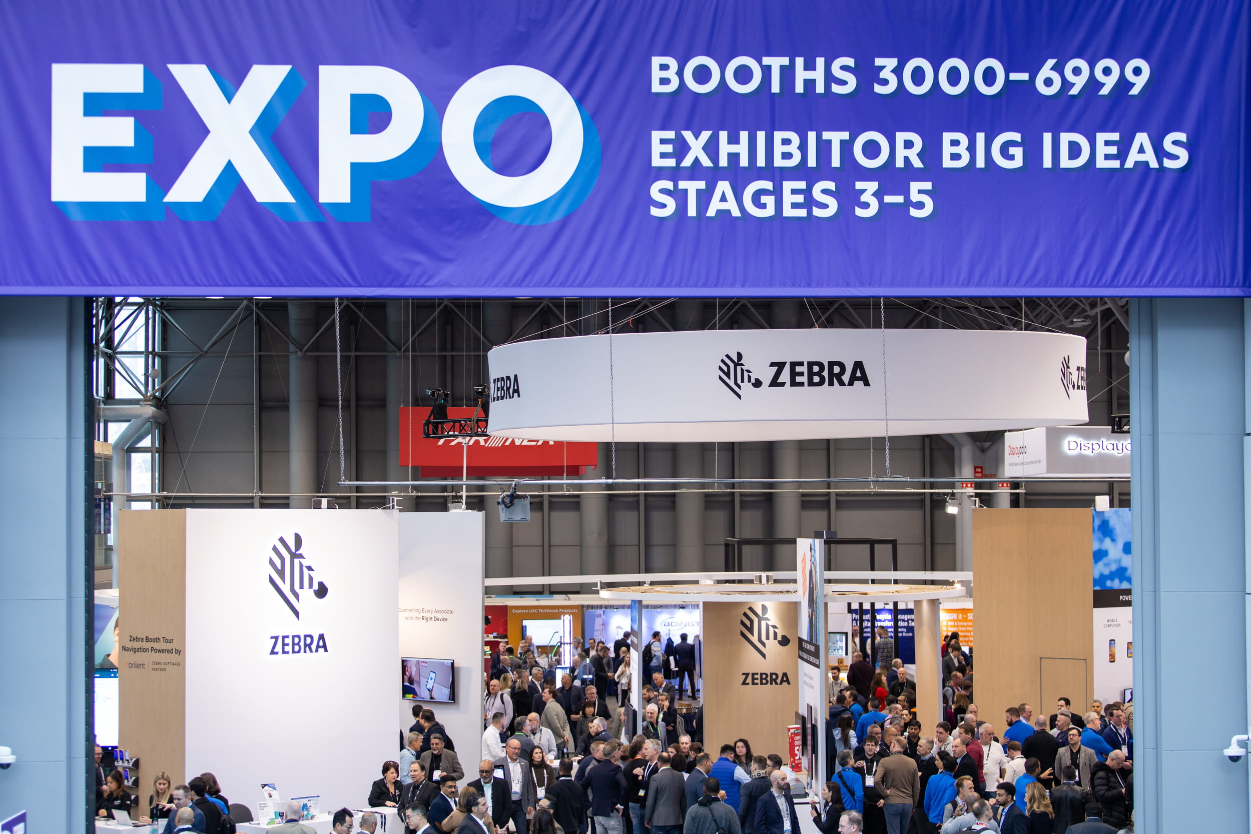 Vue de l’espace d’exposition du NRF 2025 avec une foule de visiteurs devant le stand de Zebra Technologies, sous une grande bannière "EXPO".