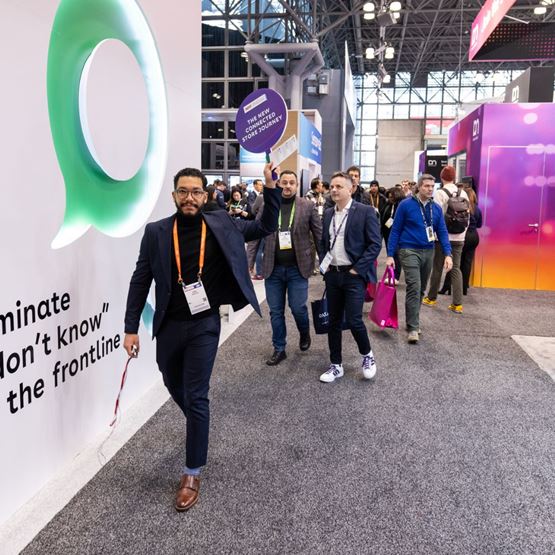 Un groupe de visiteurs avance dans les allées du NRF 2025, mené par un participant brandissant un panneau 'The New Connected Store Journey'.